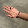 Green tourmaline and 9k gold pyramid bracelet worn on the wrist alongside a dark stone ring.