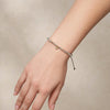 Labradorite evil eye bracelet worn on the wrist, showing delicate grey beads, small 9k gold accents and black cord ends.