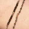 Close-up of GOLDEN bracelet’s faceted pyrite beads, knotted khaki cord and crystal pavé bar, layered on the wrist.