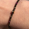 Tourmaline bracelet on the wrist, showing dark green beads, pink accents and a central 9k gold pyramid.”
Charm close-up: “Close-up of the 9k gold pyramid with triangular pavé inset between faceted green tourmaline beads.