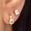 Close-up of a moonstone stud worn above a gold hoop earring with a pale square gemstone